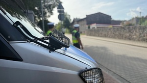 Radiowóz policyjny z policjantami w tle