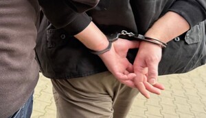 Osoba zatrzymana, na zdjęciu ręce, na których założone są kajdanki na rękach