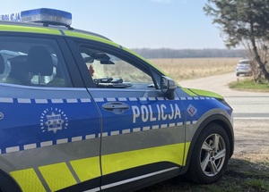 Radiowóz policyjny oznakowany zaparkowany przy drodze