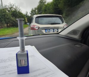 Trzy zdjęcia pojazdu marki Ford Kuga, koloru jasnego. Pierwsze zdjęcie pojazd zaparkowany, za nim oznakowany radiowóz, na drugim zdjęciu narkotester z wynikiem badania, na trzecim zdjęciu zaparkowany pojazdu Ford Kuga koloru jasnego.