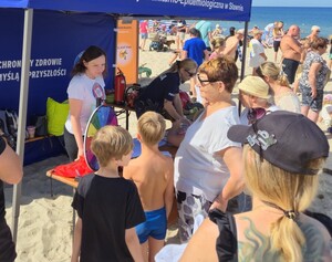 Sześć zdjęć przedstawiających działania na plaży - policjant w grantantowym mundurze, strażak w mundurze i przedstawiciele Wodnego Ochotniczego Pogotowia Rarunkowego, w tle dzieci i namiot profilaktyczny,