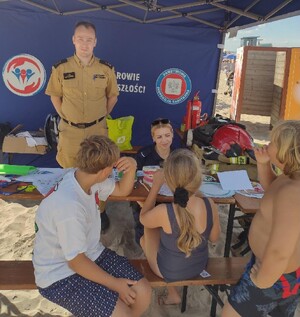Sześć zdjęć przedstawiających działania na plaży - policjant w grantantowym mundurze, strażak w mundurze i przedstawiciele Wodnego Ochotniczego Pogotowia Rarunkowego, w tle dzieci i namiot profilaktyczny,